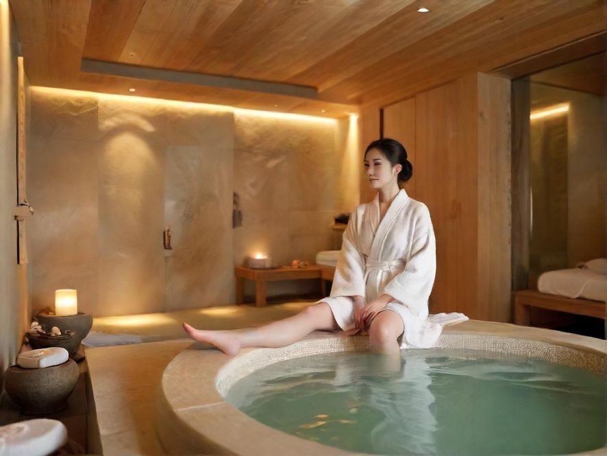 一位专业的按摩师正在为客人进行精油按摩，特写镜头展现了轻柔的双手和客人的放松表情，柔和的暖光洒满舒适的SPA室。